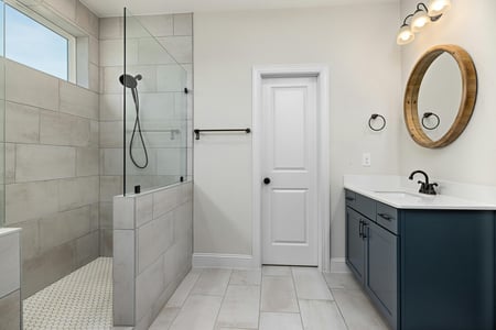 Minimalist bathroom remodel with wood mirror and glass shower by SmartSpaces ADUs in Brookhaven, GA