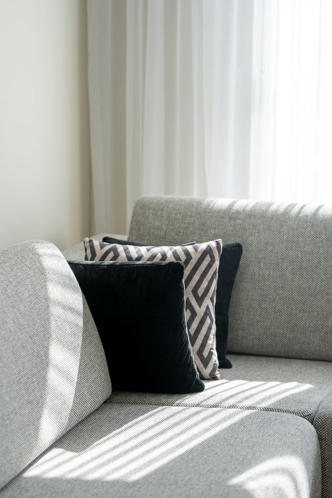 Sunlit gray couch with modern throw pillows in a custom home by Smart Spaces ADUs in Tucker, GA - stock Sunlit gray couch with modern throw pillows in a custom home by Smart Spaces ADUs in Tucker, GA - stock